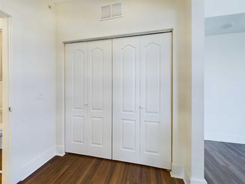 Apartments in Lebanon, IN A white closet with double doors in a room with light-colored walls and hardwood flooring.