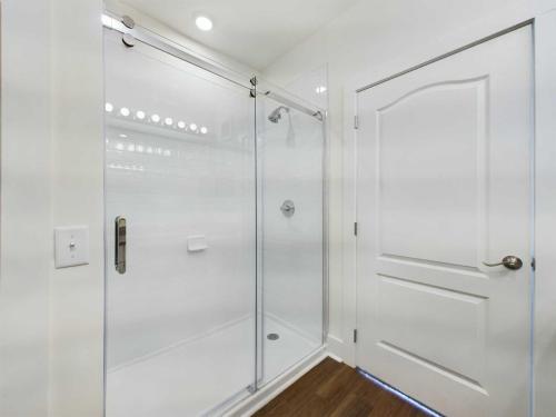 Apartments in Lebanon, IN Modern bathroom with a glass-enclosed shower, white tiled walls, and a white wooden door. The space is brightly lit with recessed lighting.