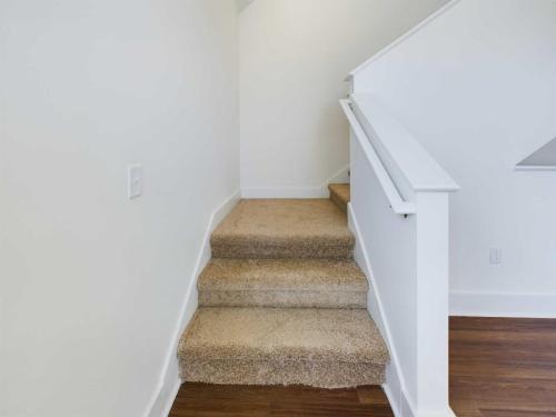 Apartments in Lebanon, IN A small carpeted staircase with beige flooring and white walls leading to a higher level in a house.