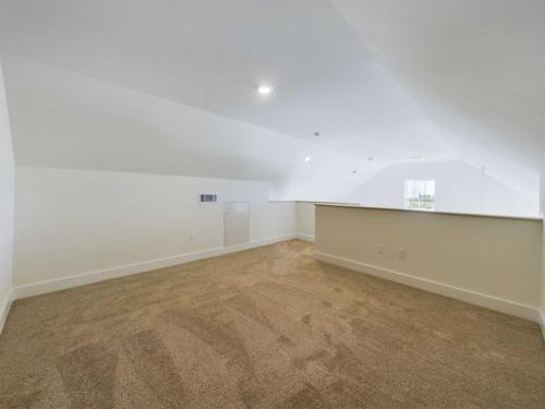 Apartments in Lebanon, IN An empty, carpeted attic space with white walls, a small window, and a half-wall dividing the space.