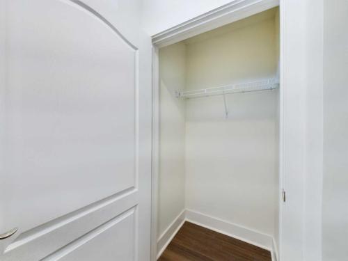 Apartments in Lebanon, IN An empty closet with white walls, a single white wire shelf, and dark wooden flooring is shown with the door open.