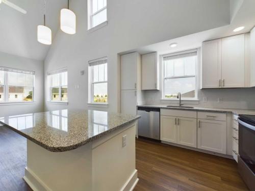 Apartments in Lebanon, IN Modern kitchen with white cabinets, granite countertops, and stainless steel appliances. The room features large windows allowing ample natural light and a dark wood floor.