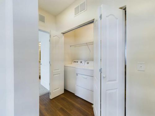 Apartments in Lebanon, IN A small laundry room with bi-fold doors features a white washing machine and dryer set on a hardwood floor.