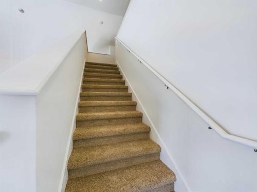 Apartments in Lebanon, IN Carpeted staircase with white walls on both sides, handrails are installed on the right side. The staircase leads upward, turning left at the top.