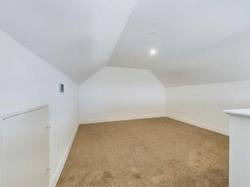 Apartments in Lebanon, IN A small, empty room with sloped white walls, beige carpet flooring, a small vent on the left wall, and a recessed light in the ceiling.