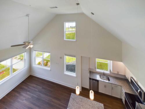 Apartments in Lebanon, IN A view from above of a modern kitchen and living area with vaulted ceilings, large windows, wood flooring, and pendant lighting over the kitchen island.