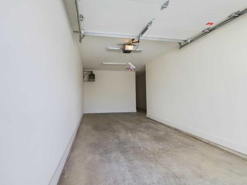 Apartments in Lebanon, IN An empty, clean garage with white walls, a concrete floor, and an open garage door. The ceiling has lighting fixtures and an automatic garage door opener.