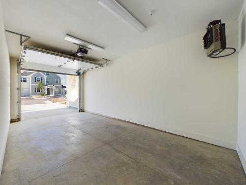 Apartments in Lebanon, IN An empty garage with an open door, concrete floor, and overhead lighting. The exterior view shows part of a residential neighborhood.