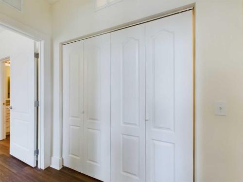 Apartments in Lebanon, IN A closed white bi-fold closet door is in a bright room with white walls and dark wood flooring. An open doorway on the left leads to a bathroom.