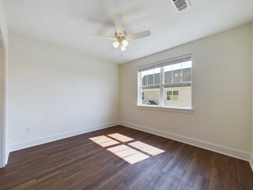 Apartments in Lebanon, IN Empty room with a ceiling fan, hardwood floor, and a window with blinds. Sunlight is casting shadows on the floor. Walls are painted white.