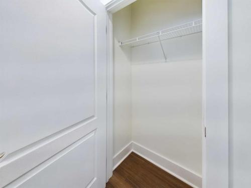 Apartments in Lebanon, IN A small, empty closet with white walls, a single wire shelf, and wooden flooring, viewed through an open white door.