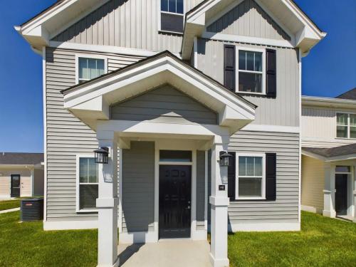 Indiana, Boone County, Lebanon Apartments for rent A modern two-story house with gray siding, white trim, and a covered front porch. Black shutters and a central black front door are visible. The lawn is green under a clear blue sky. See all available apartments for rent at Hickory Cottages in Indiana Boone County Lebanon, Hickory Cottages has rental units ranging from 664-1420 sq ft