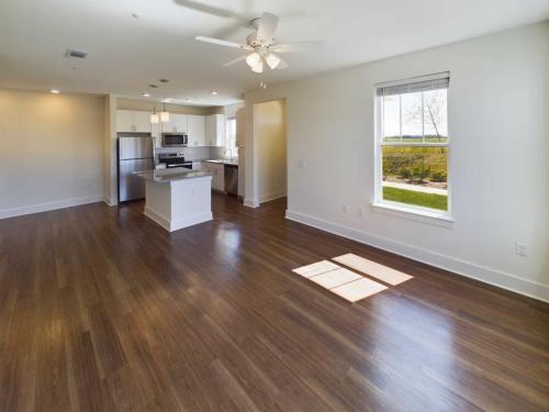 Indiana, Boone County, Lebanon Apartments for rent An empty, modern kitchen and living area with wood flooring, stainless steel appliances, a ceiling fan, and large window showing a garden view. See all available apartments for rent at Hickory Cottages in Indiana Boone County Lebanon, Hickory Cottages has rental units ranging from 664-1420 sq ft