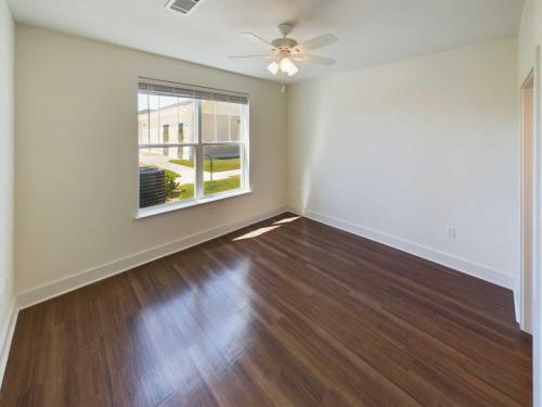 Indiana, Boone County, Lebanon Apartments for rent Empty room with light brown wood flooring, a ceiling fan with lights, and a large window with blinds. Walls are painted white, and natural light illuminates the space. See all available apartments for rent at Hickory Cottages in Indiana Boone County Lebanon, Hickory Cottages has rental units ranging from 664-1420 sq ft