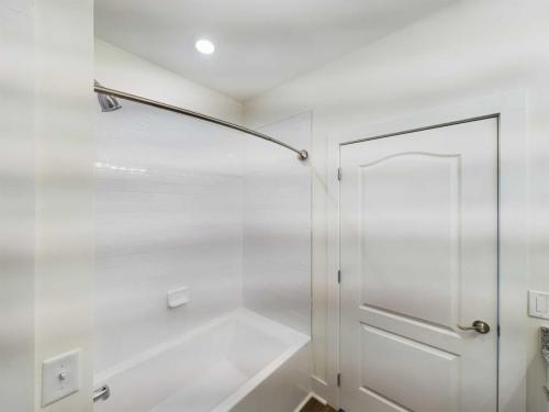 Indiana, Boone County, Lebanon Apartments for rent A white bathroom with a bathtub, curtain rod, tiled walls, and a closed door. See all available apartments for rent at Hickory Cottages in Indiana Boone County Lebanon, Hickory Cottages has rental units ranging from 664-1420 sq ft