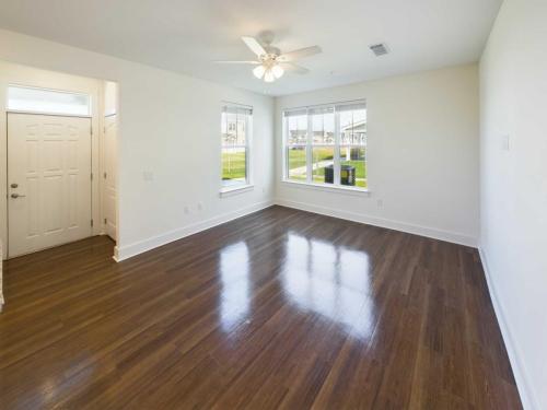 Two Bedroom Apartment, #10-102, Shot Clock, 1150 sqftIndiana, Boone County, Lebanon Apartments for rent An empty room with wooden flooring, two windows, a ceiling fan, and an entrance door. Natural light illuminates the space. See all available apartments for rent at Hickory Cottages in Indiana Boone County Lebanon, Hickory Cottages has rental units ranging from 664-1420 sq ft