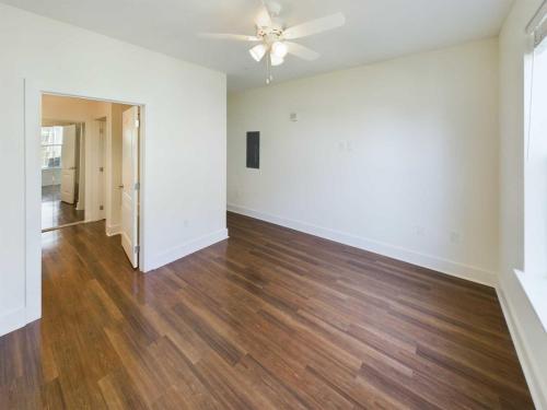 Indiana, Boone County, Lebanon Apartments for rent An empty room with wooden floors, white walls, a ceiling fan with lights, and a doorway leading to another area. Large window on the right side. See all available apartments for rent at Hickory Cottages in Indiana Boone County Lebanon, Hickory Cottages has rental units ranging from 664-1420 sq ft