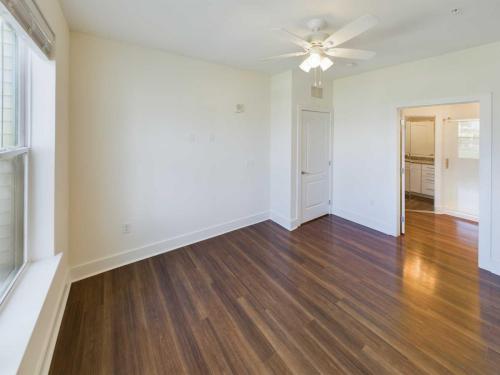 Indiana, Boone County, Lebanon Apartments for rent Empty room with wooden floor, white walls, ceiling fan, and a door leading to a bathroom with a visible sink and mirror. See all available apartments for rent at Hickory Cottages in Indiana Boone County Lebanon, Hickory Cottages has rental units ranging from 664-1420 sq ft