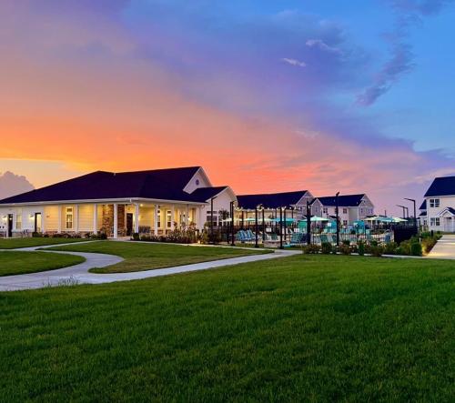 See all available apartments for rent at Hickory Cottages in Lebanon, IN. Hickory Cottages has rental units ranging from 664-1420 sq ft A residential area at sunset with modern, single-story homes and outdoor amenities, including a swimming pool and green lawns. The sky displays a gradient of orange and blue hues.
