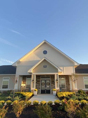 Indiana, Boone County, Lebanon Apartments for rent A modern house with a triangular roof, two glass front doors, and a landscaped garden with yellow flowers. The sky is clear and blue. See all available apartments for rent at Hickory Cottages in Indiana Boone County Lebanon, Hickory Cottages has rental units ranging from 664-1420 sq ft