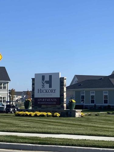 Indiana, Boone County, Lebanon Apartments for rent Sign for Hickory Cottages Apartments surrounded by grass and flowers, with buildings in the background under a clear blue sky. See all available apartments for rent at Hickory Cottages in Indiana Boone County Lebanon, Hickory Cottages has rental units ranging from 664-1420 sq ft