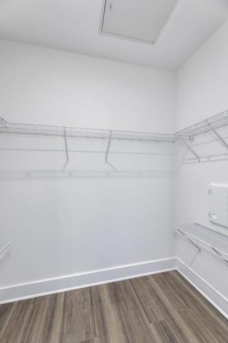 Apartments in Lebanon, IN A large empty closet with white walls, wire shelving along the sides, and hardwood flooring.