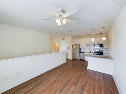 Apartments in Lebanon, IN Step into apartments for rent in Lebanon, Indiana, featuring a modern kitchen and living area adorned with hardwood floors, white walls, a ceiling fan, stainless steel appliances, granite countertops, and stylish pendant lights above the kitchen island.